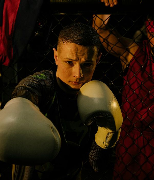 Man performing a strength exercise in a dark room with blue light accents.